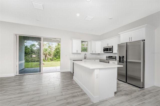 kitchen featuring stainless steel appliances, a center island, sink, and white cabinets