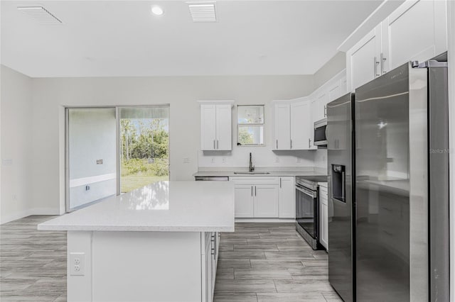 kitchen with white cabinetry, sink, a kitchen island, and appliances with stainless steel finishes