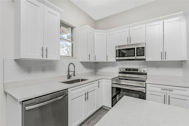 kitchen with sink, light stone counters, white cabinets, stainless steel appliances, and backsplash