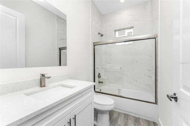 full bathroom featuring vanity, bath / shower combo with glass door, and toilet