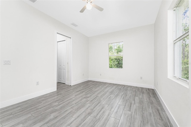 unfurnished room featuring a wealth of natural light, ceiling fan, and light hardwood / wood-style flooring