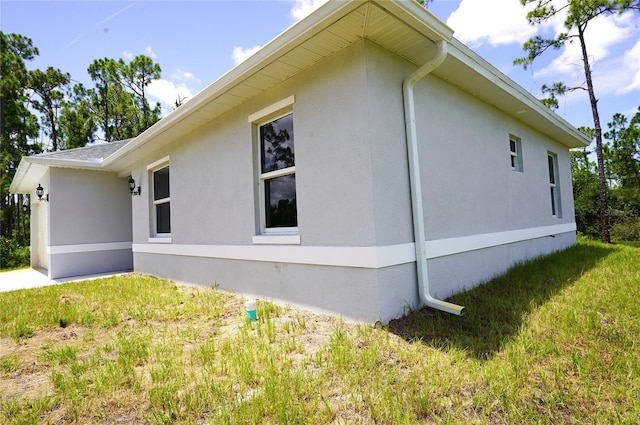 view of side of home featuring a yard and stucco siding