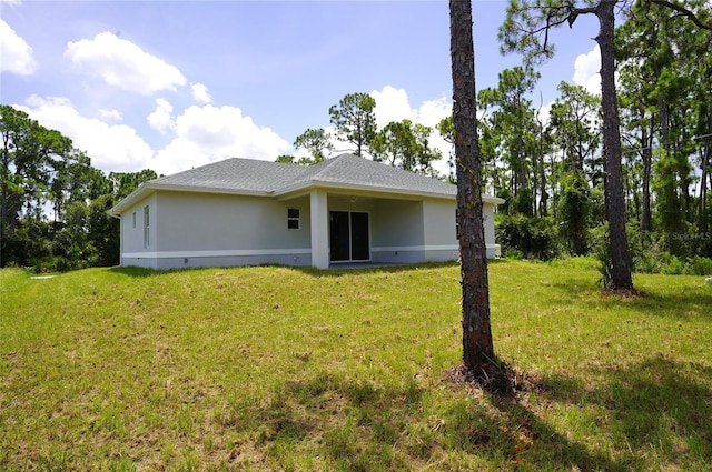 back of property with a shingled roof, crawl space, a yard, and stucco siding