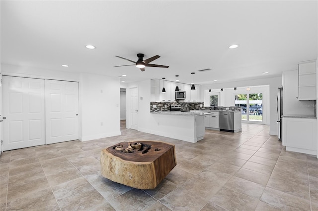 kitchen featuring kitchen peninsula, white cabinets, stainless steel appliances, and pendant lighting