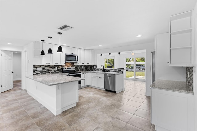 kitchen with hanging light fixtures, kitchen peninsula, stainless steel appliances, sink, and white cabinetry