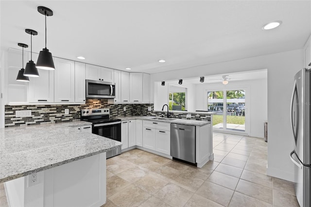 kitchen with white cabinetry, light stone counters, appliances with stainless steel finishes, and kitchen peninsula