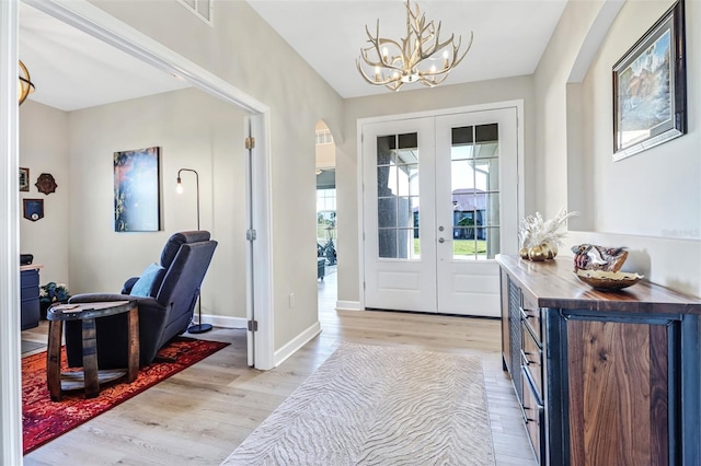 entrance foyer with an inviting chandelier, light hardwood / wood-style flooring, and french doors