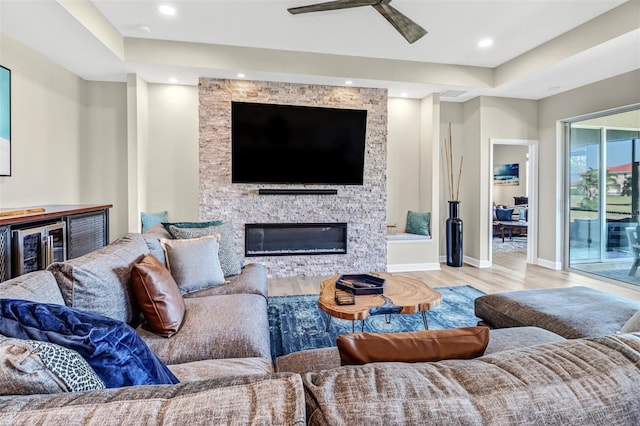 living room featuring a fireplace, ceiling fan, and light hardwood / wood-style floors