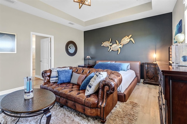 bedroom featuring light hardwood / wood-style flooring and a tray ceiling