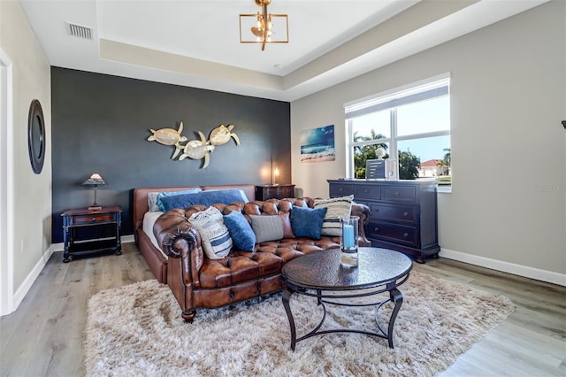 bedroom featuring a tray ceiling, a notable chandelier, and light hardwood / wood-style floors