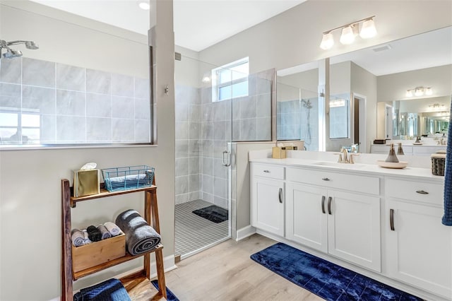 bathroom featuring wood-type flooring, a shower with shower door, and vanity