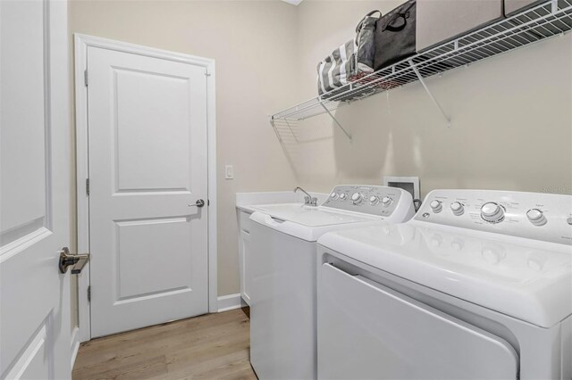 clothes washing area featuring cabinets, sink, light hardwood / wood-style flooring, and washer and dryer