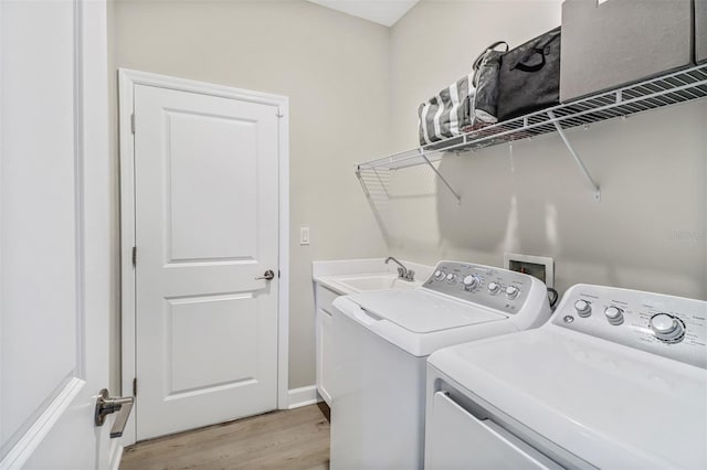 laundry area with light hardwood / wood-style floors, sink, cabinets, and washing machine and clothes dryer