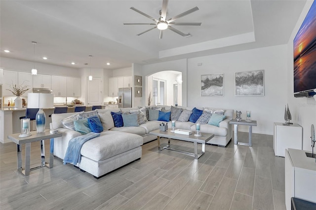 living room featuring ceiling fan and a raised ceiling