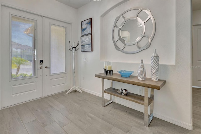 foyer entrance with french doors and light hardwood / wood-style floors