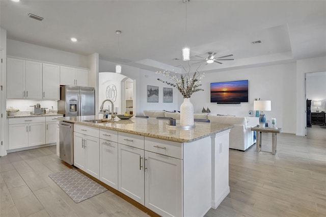 kitchen with a center island with sink, white cabinets, and appliances with stainless steel finishes