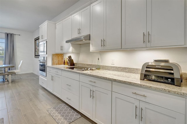 kitchen featuring white cabinetry, light stone counters, light hardwood / wood-style floors, and appliances with stainless steel finishes