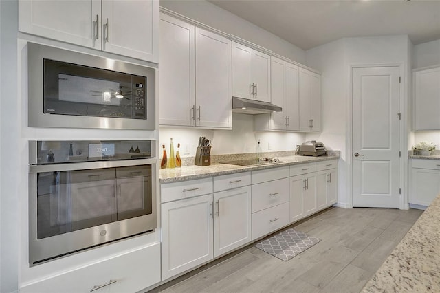 kitchen with built in microwave, oven, and white cabinets