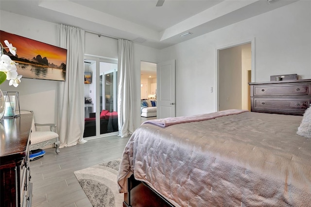 bedroom with ceiling fan, a tray ceiling, and access to exterior