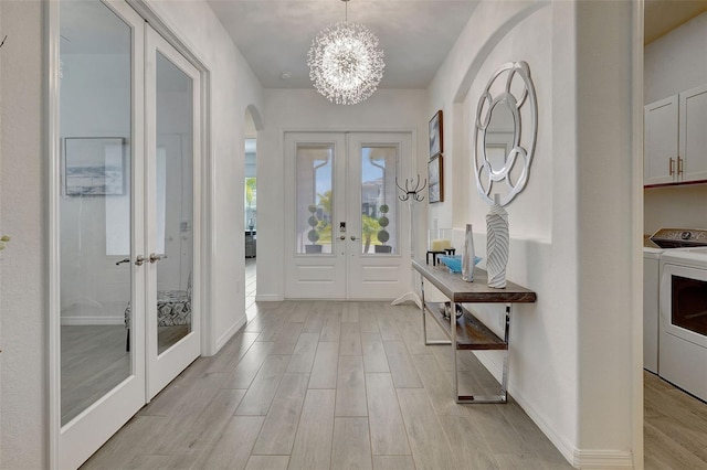 entrance foyer featuring an inviting chandelier, french doors, and washer and dryer