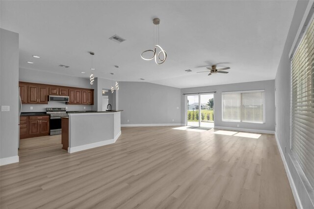 kitchen with stainless steel appliances, visible vents, open floor plan, light wood finished floors, and dark countertops