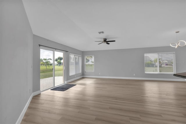 unfurnished living room featuring light wood-style floors, visible vents, baseboards, and ceiling fan with notable chandelier