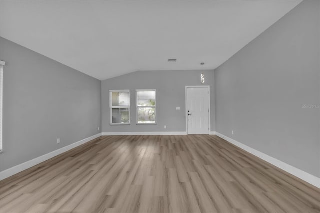 unfurnished living room featuring vaulted ceiling, light wood finished floors, visible vents, and baseboards