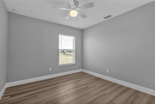 unfurnished room with a ceiling fan, visible vents, baseboards, and wood finished floors