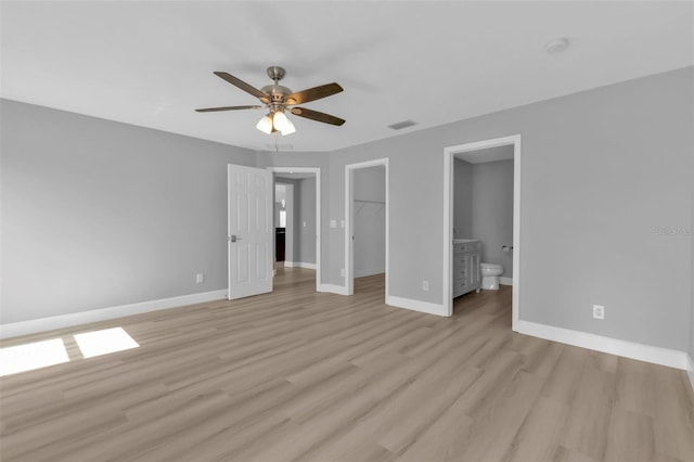 unfurnished bedroom featuring visible vents, baseboards, a spacious closet, a closet, and light wood finished floors