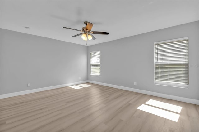 spare room featuring light wood-style floors, baseboards, and a ceiling fan