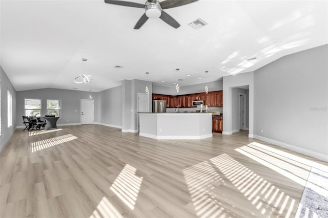 unfurnished living room with baseboards, visible vents, vaulted ceiling, light wood-style floors, and ceiling fan with notable chandelier