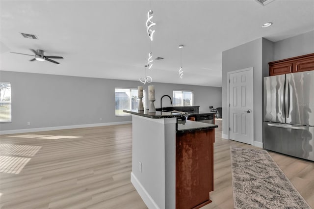 kitchen with a sink, visible vents, open floor plan, freestanding refrigerator, and light wood finished floors