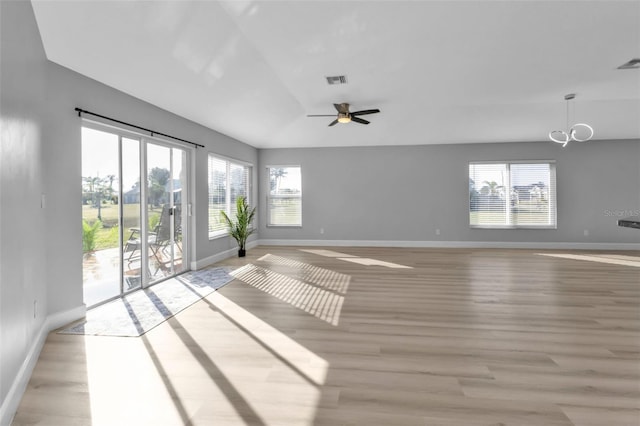 unfurnished living room featuring light wood finished floors, a wealth of natural light, and baseboards