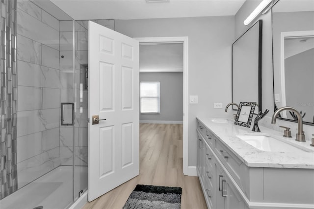 full bath with a shower stall, baseboards, a sink, and wood finished floors