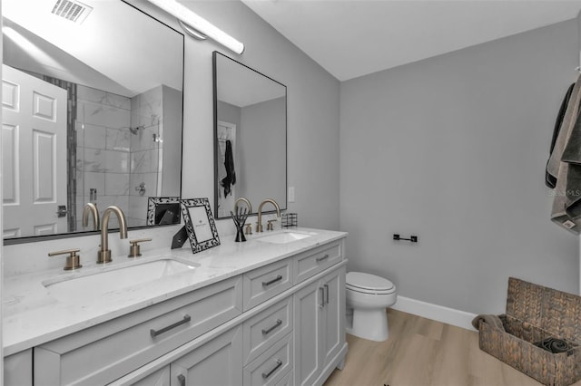 full bath featuring visible vents, a sink, a shower stall, and wood finished floors