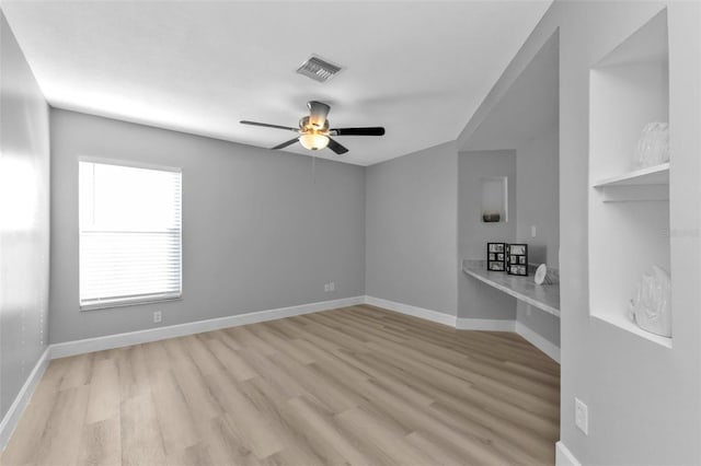 empty room with a ceiling fan, baseboards, visible vents, and wood finished floors