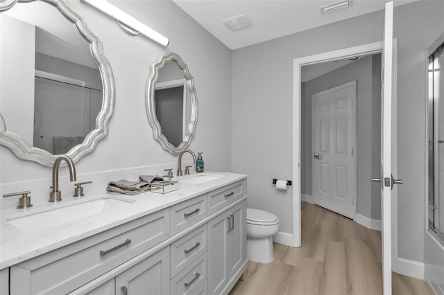 full bathroom featuring visible vents, a sink, toilet, and wood finished floors