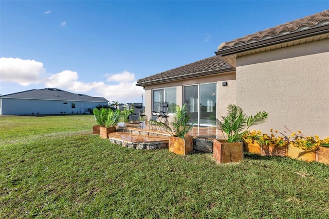 rear view of property with a lawn and stucco siding