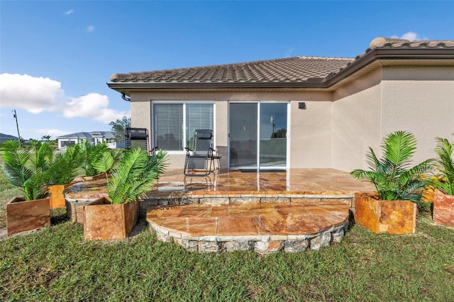 back of property featuring a patio area, a tiled roof, and stucco siding