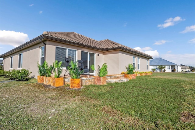 back of house with a yard, a tile roof, and stucco siding