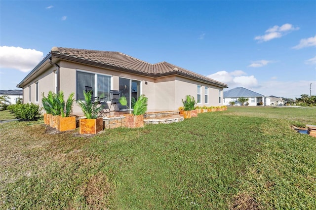 rear view of house with a tile roof, a lawn, and stucco siding