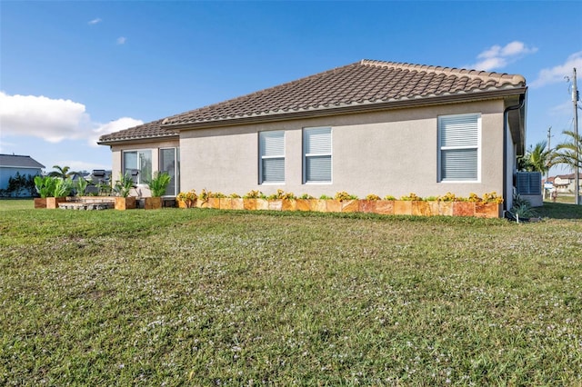 view of property exterior featuring a yard, a tiled roof, and stucco siding