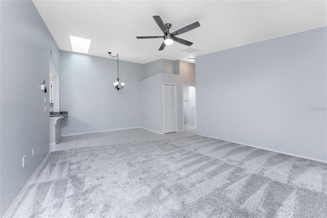 empty room featuring a skylight, ceiling fan with notable chandelier, and carpet flooring