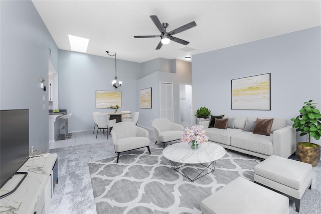 living room featuring a skylight and ceiling fan with notable chandelier