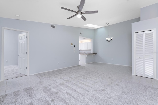 unfurnished living room with ceiling fan with notable chandelier and light tile patterned floors