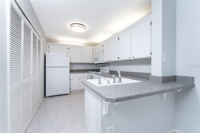 kitchen featuring a breakfast bar, white appliances, light tile patterned floors, kitchen peninsula, and white cabinets