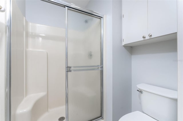 bathroom featuring a shower with shower door and toilet