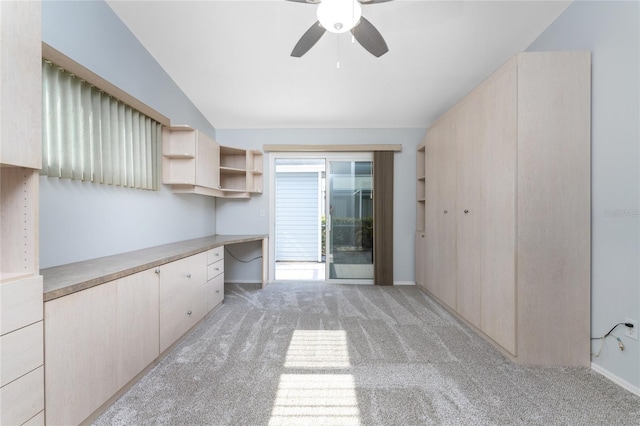 interior space with built in desk, vaulted ceiling, light colored carpet, and ceiling fan