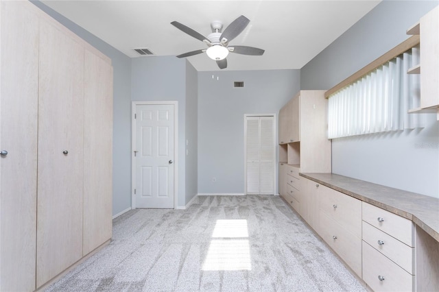 unfurnished bedroom featuring light carpet, two closets, and ceiling fan