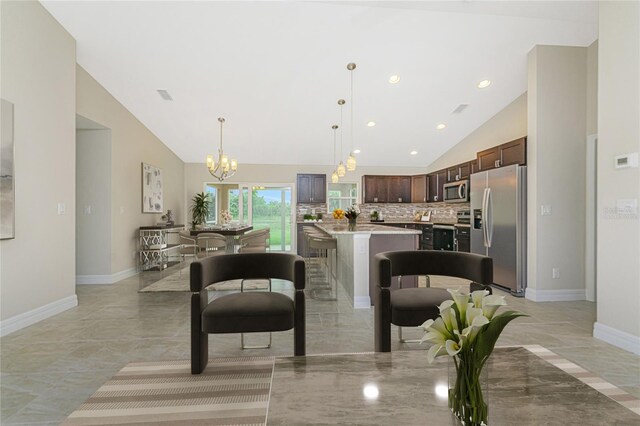 kitchen with appliances with stainless steel finishes, hanging light fixtures, light tile patterned floors, a kitchen island, and decorative backsplash